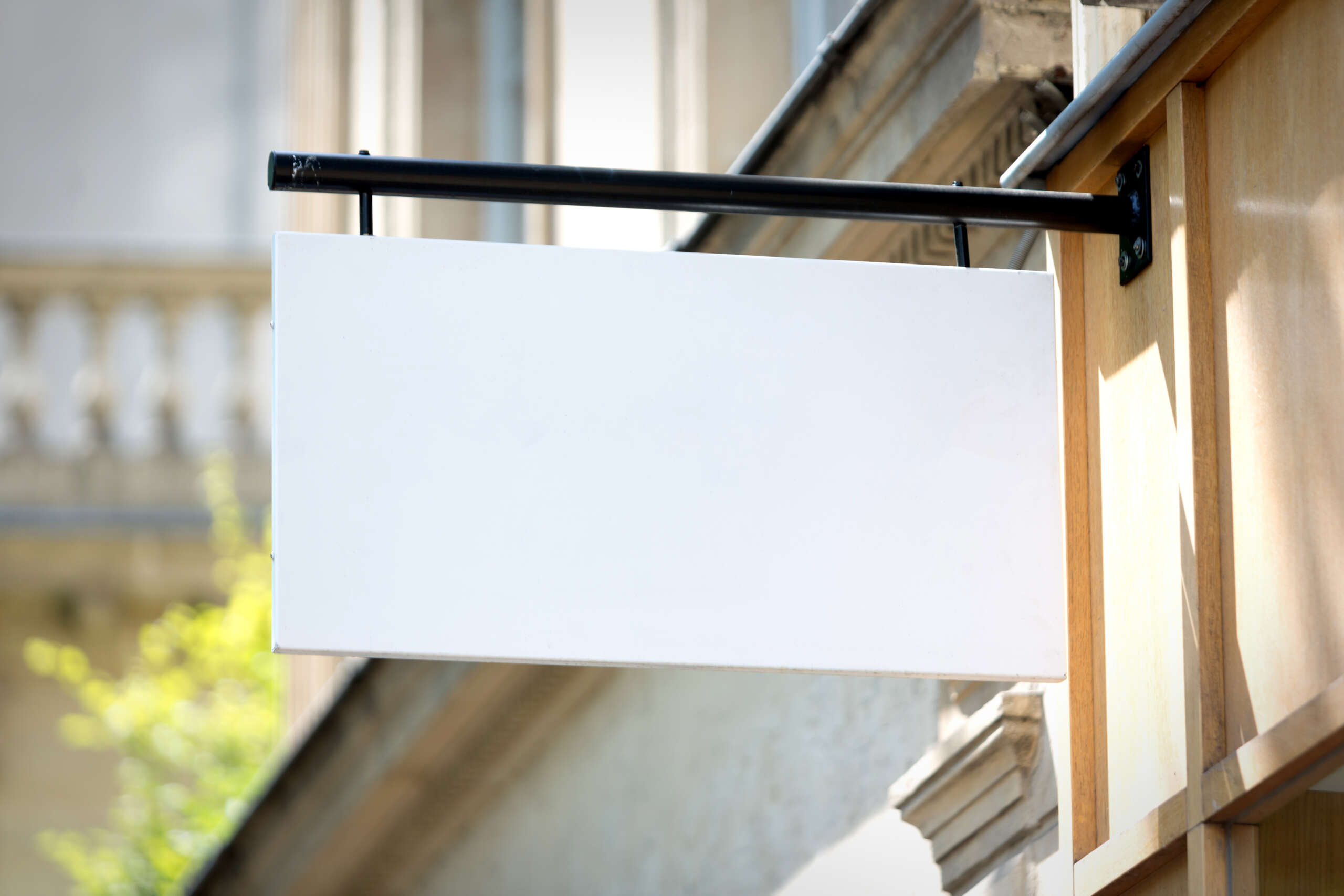 Blank store sign hanging outside a shop, representing the concept of choosing store names. Feature image for a blog titled '100+ Store Names for Your Business.'