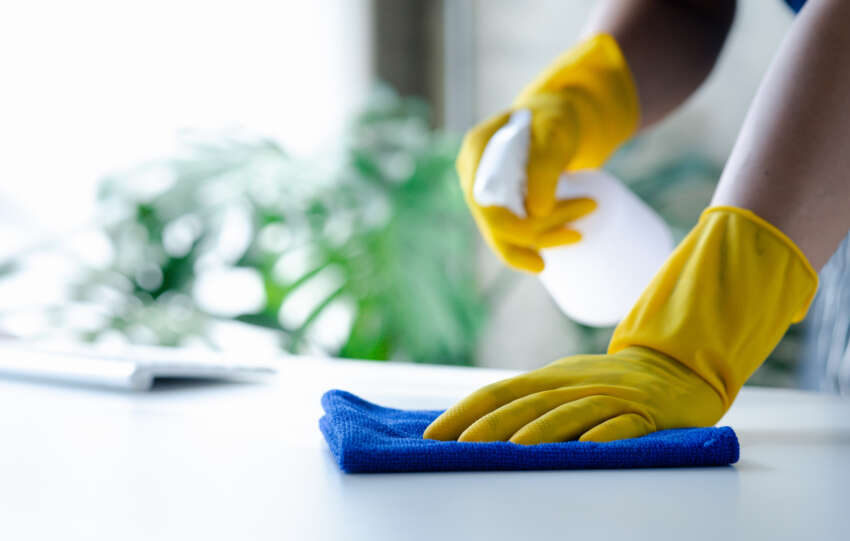 How to Start a Cleaning Business: An image of a person wiping off a desk.